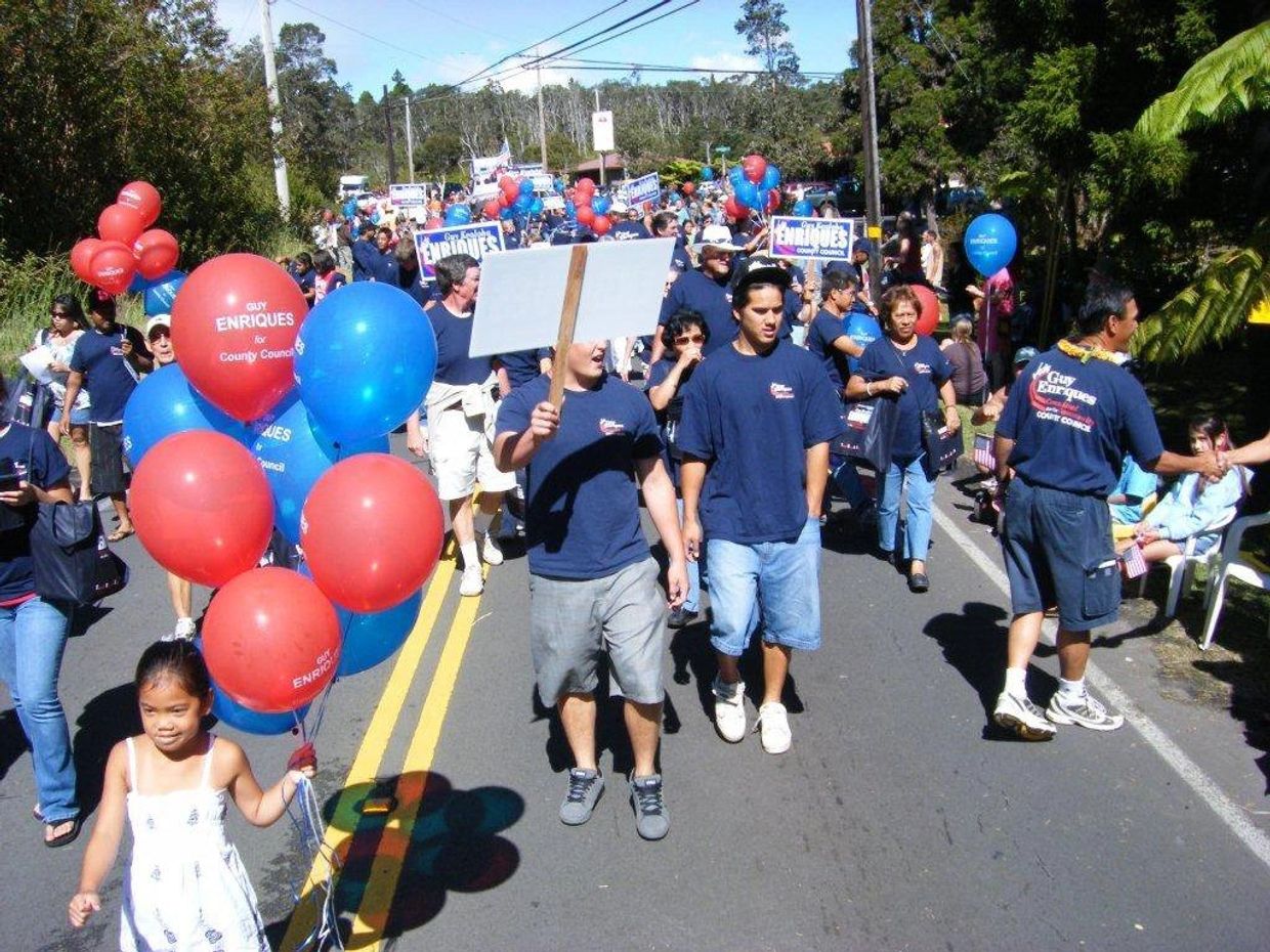 A group marching in support of Guy Enriques for County Council with balloons and signs.