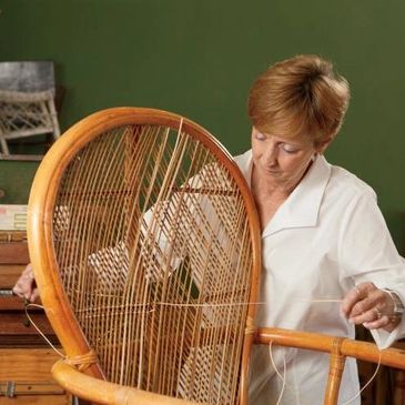 Employee repairing the canning on a woven wood chair.