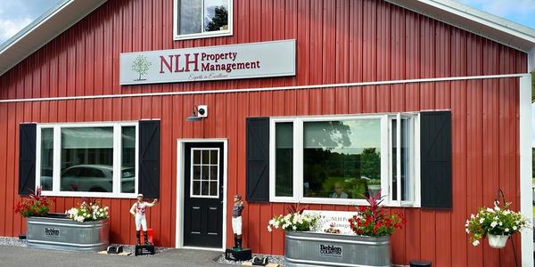 Red building with NLH Property Management sign and decorative jockey statues outside.