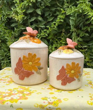 Two ceramic jars with flower and butterfly designs.