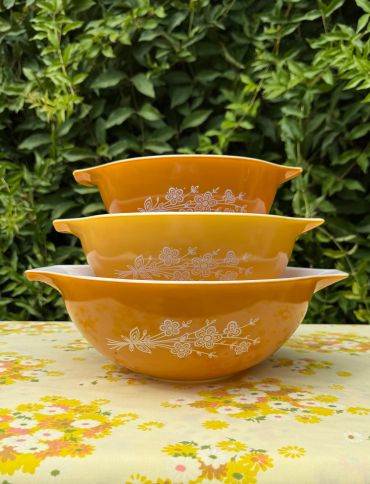 Stacked vintage orange bowls with floral patterns.