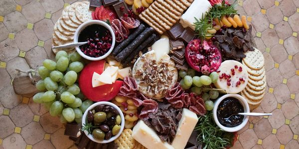 A colorful charcuterie board with cheeses, fruits, and crackers.