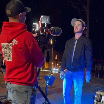 Two men filming a scene at night with lights and camera.