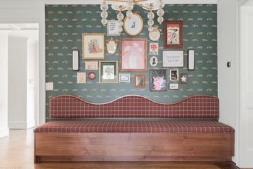 Cozy wooden bench with plaid cushion under a gallery wall of framed art and quotes.
