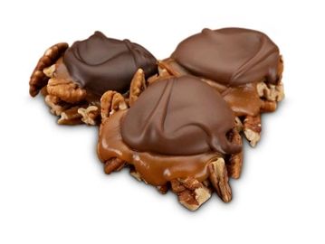 Three pecan turtle candies with chocolate and caramel.