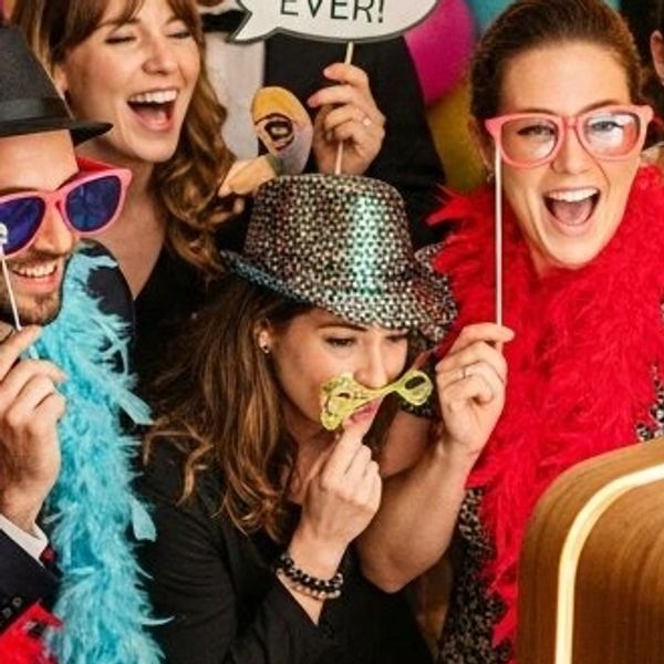 Friends having fun with photo booth props and costumes at a party.