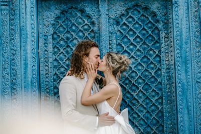A couple sharing a tender moment in front of an ornate blue door.