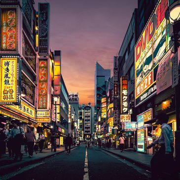 Busy city street with neon signs at dusk.