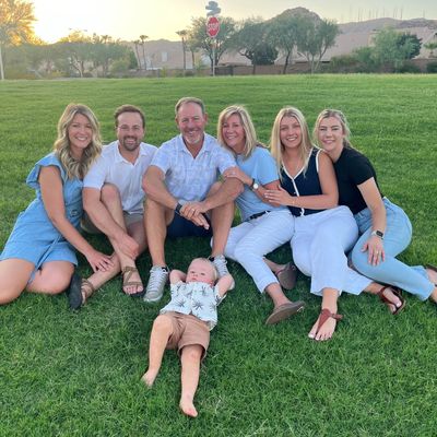 A happy family sitting together on grass during sunset.