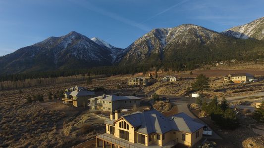 Custom mountain home under construction in a scenic valley surrounded by snow-capped peaks, built by