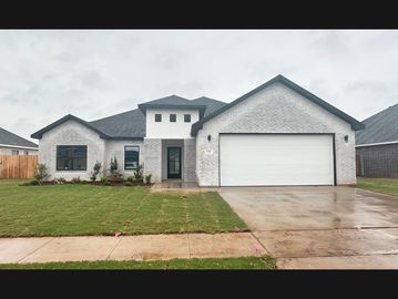 Modern single-story white brick house with a two-car garage and a wet driveway.