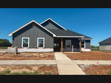 Newly constructed house with gray siding and a concrete walkway.