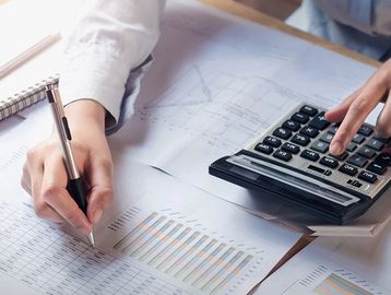 Person analyzing financial charts and using a calculator.