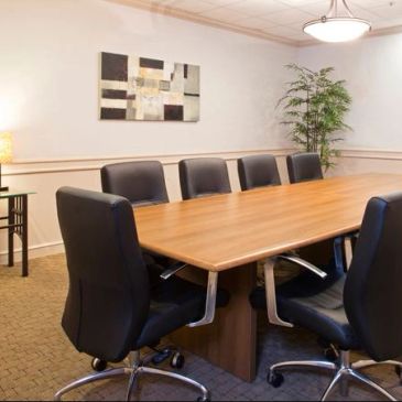 Empty modern conference room with wooden table and black chairs.