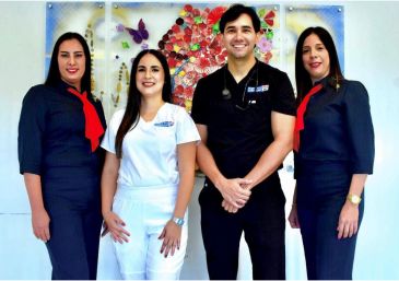 Four smiling healthcare professionals posing together indoors.