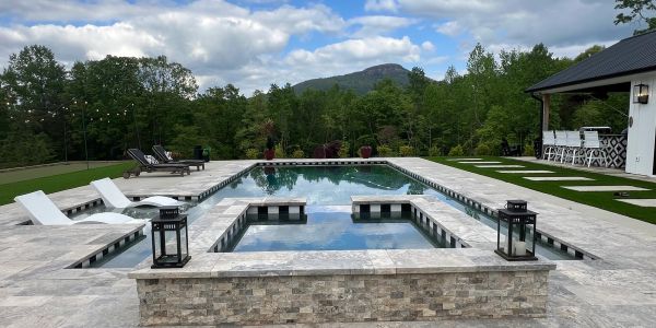 Modern outdoor pool with lounge chairs and mountain view.