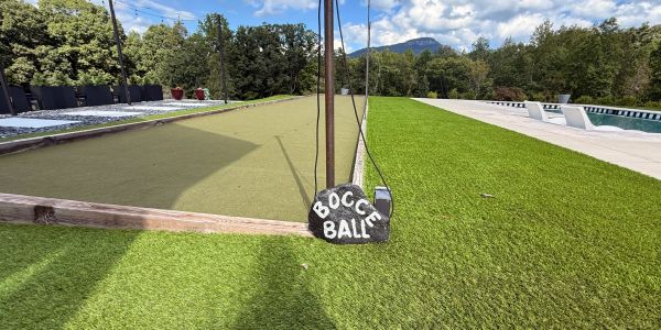 Outdoor bocce ball court with a sign and green grass.
