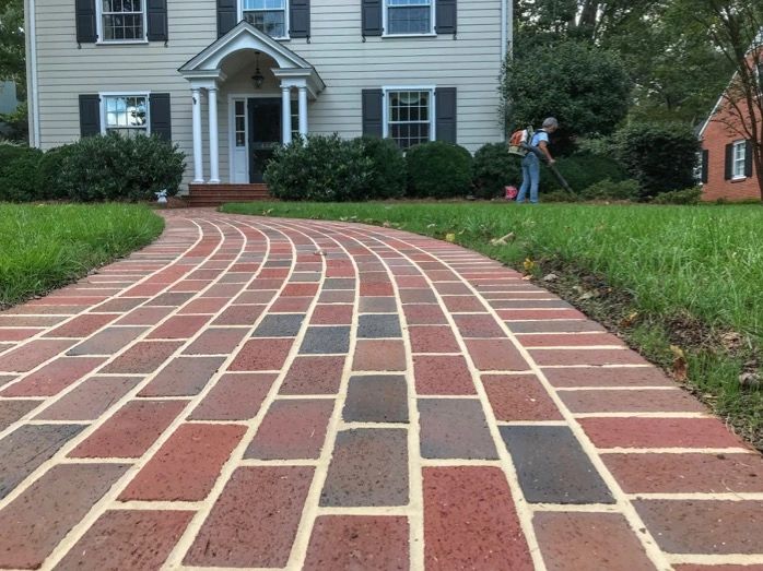 Winding brick pathway leading to a white house with a porch.