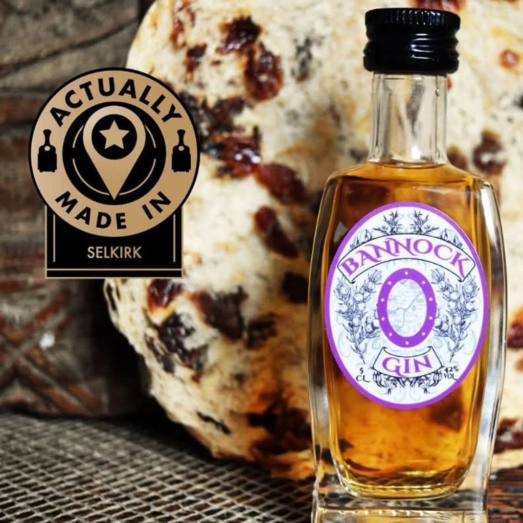 A bottle of Bannock Gin with a baked good behind and a "Actually Made in Selkirk" label.