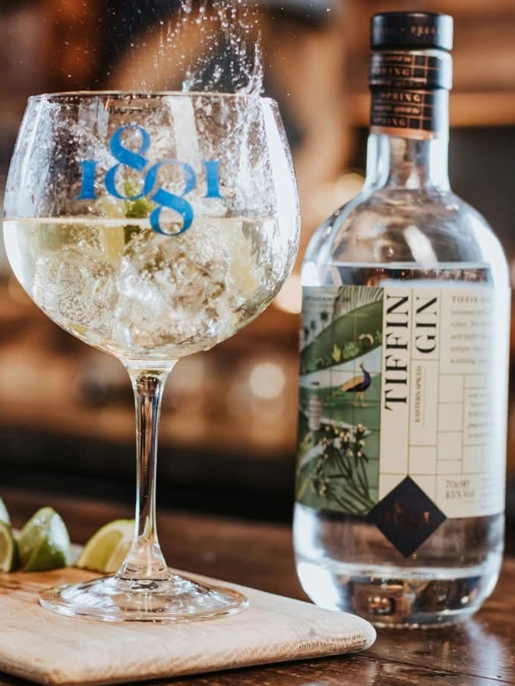 Refreshing gin and tonic with lime, mid-splash in a bar setting.