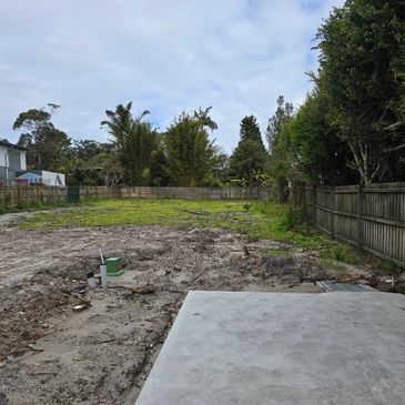 Empty backyard with patchy grass and a concrete slab on a cloudy day.
