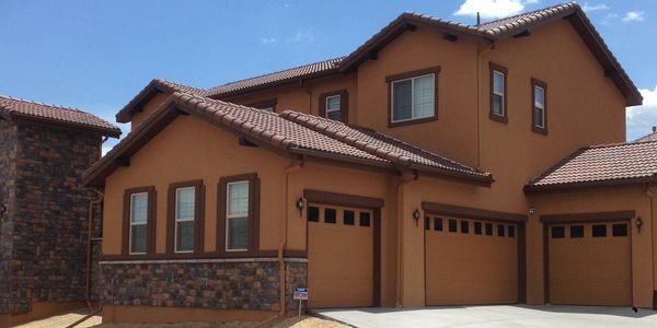 Modern two-story house with brown stucco and stone accents.