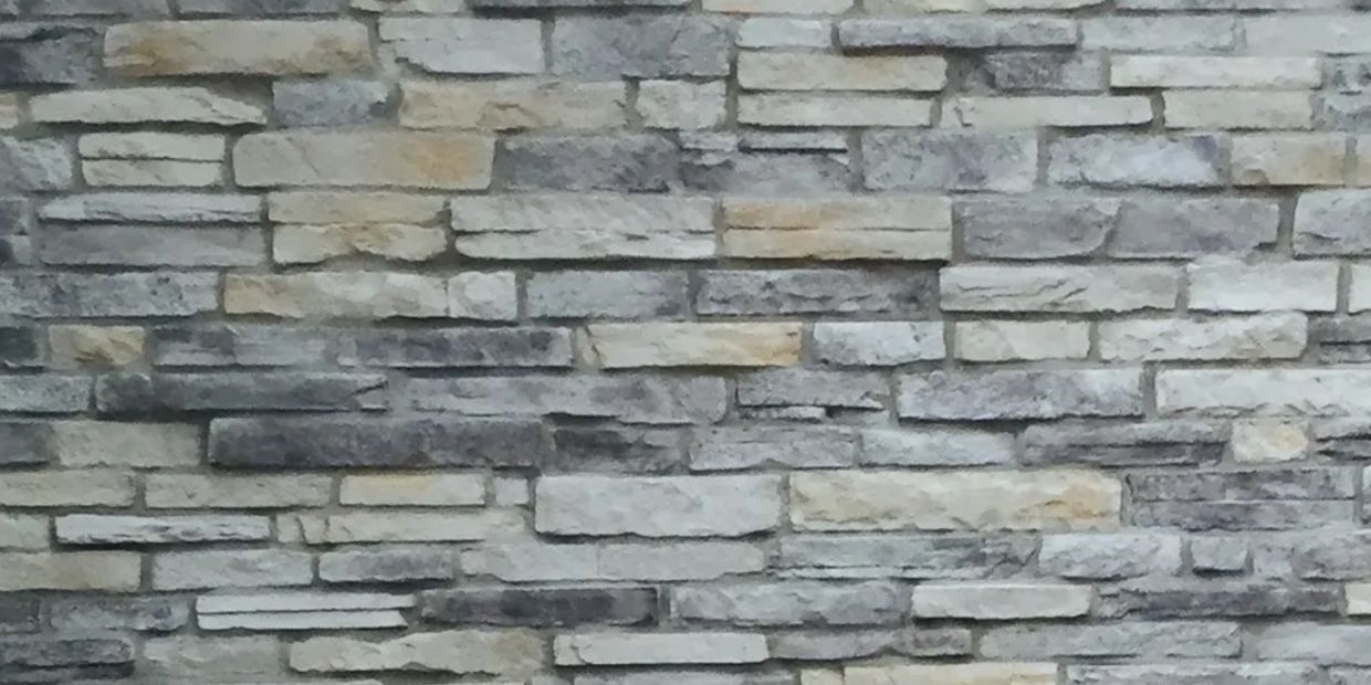 Textured stone brick wall with varying shades of gray and beige.
