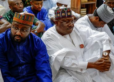 Three men in traditional attire sitting closely together in a contemplative mood.