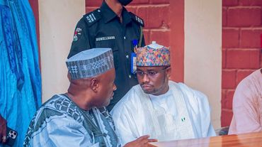 Two men in traditional Nigerian attire engaged in conversation.