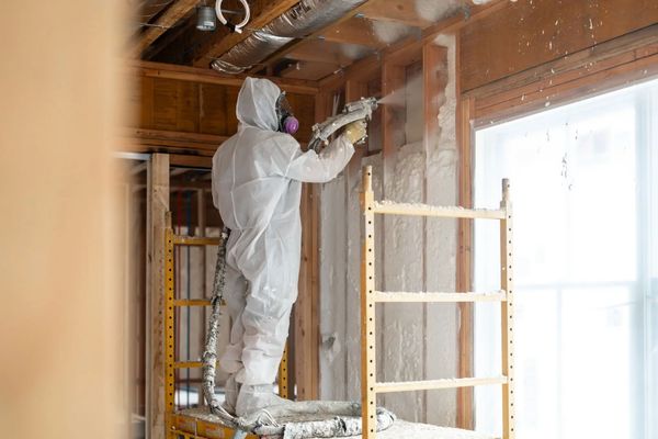 Professional in white suit spraying foam