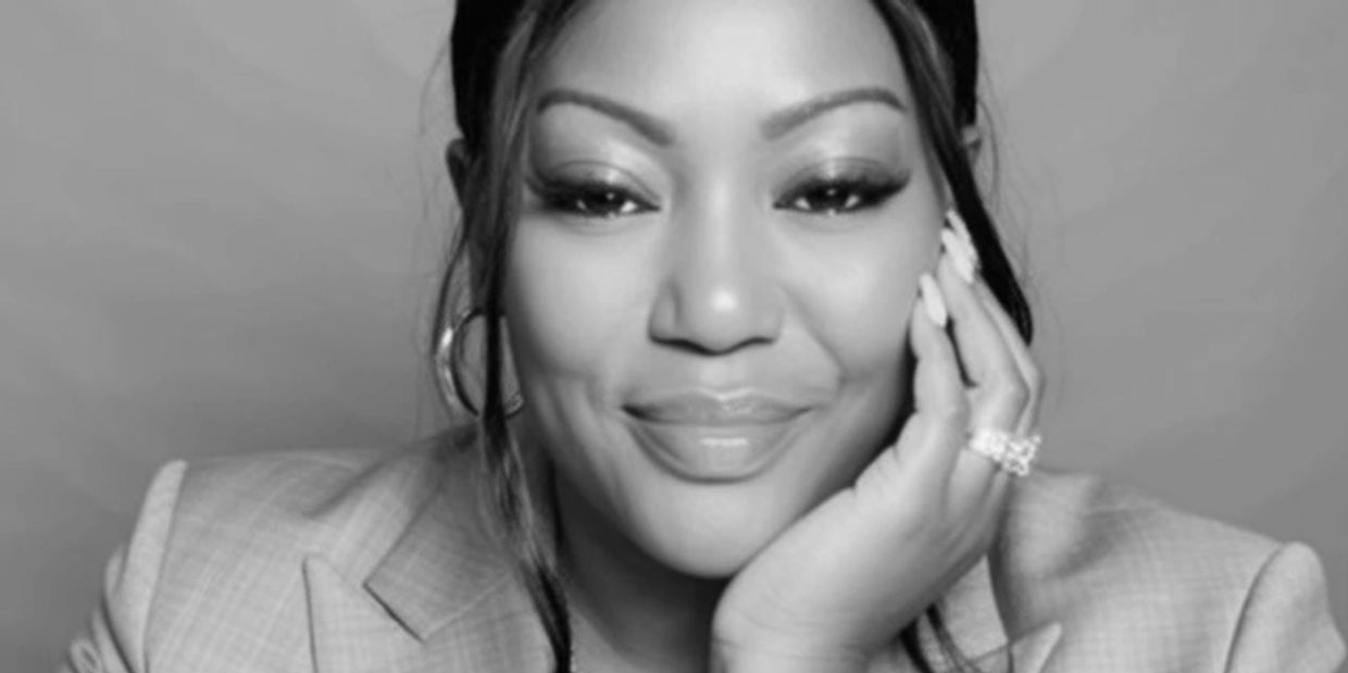 Close-up of a smiling woman with flawless makeup and manicured nails.