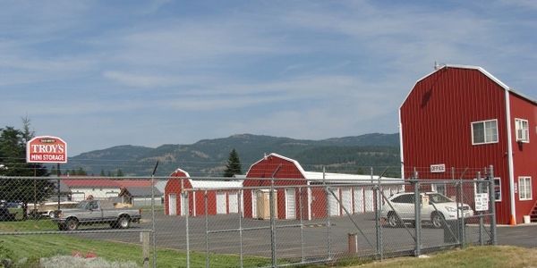 Red mini storage buildings behind a chain-link fence.