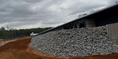 Large pile of rocks outside a long building under a cloudy sky.