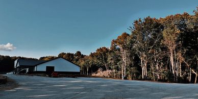 A rural building beside a forest under a clear blue sky.