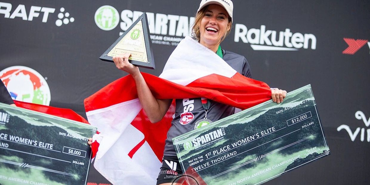 Woman holding a trophy and a large check with Canadian flag.