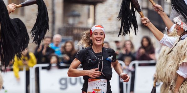 Smiling female runner celebrating while crossing the finish line.