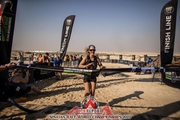 Female athlete crosses finish line in desert race.