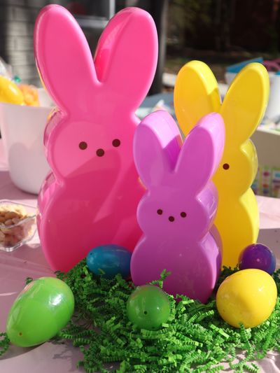 Colorful bunny-shaped containers with Easter eggs on green grass.