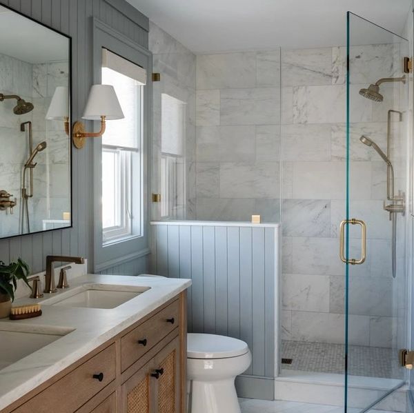 Modern bathroom with wooden vanity, glass shower, and marble tiles.