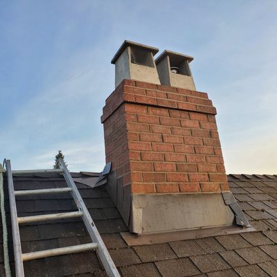 Brick chimney on a rooftop with a ladder.