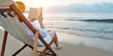 Woman reading on the beach near beautiful calm water