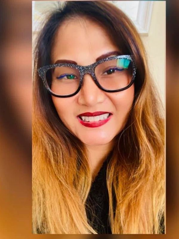 Woman with glittery glasses and red lipstick smiling.