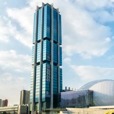 Tall modern glass skyscraper with a clear blue sky background.