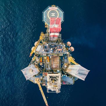 Aerial view of an offshore oil rig surrounded by deep blue sea.