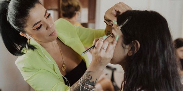 A makeup artist applies eye makeup to a client.