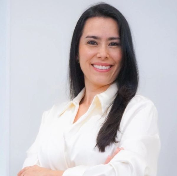 Confident woman smiling with arms crossed, wearing a white shirt.