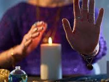 Person performing a ritual with a candle and hand gestures.