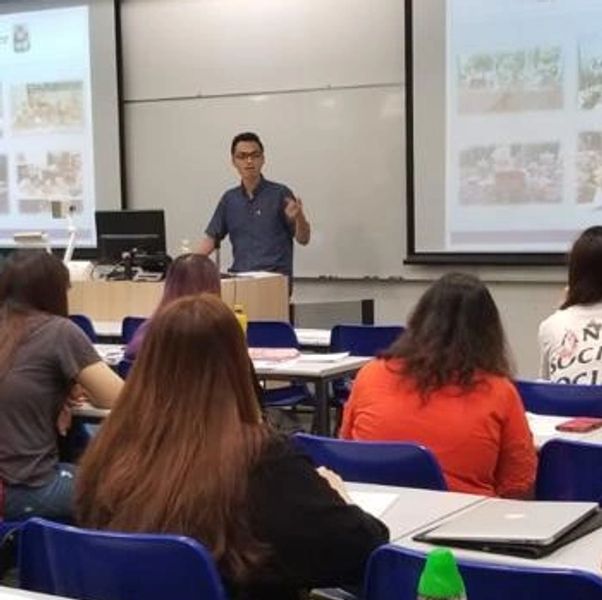 A teacher giving a lecture to students in a classroom with presentation slides.