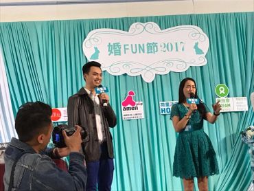 Two presenters speak on stage at a 2017 event with a photographer capturing the moment.