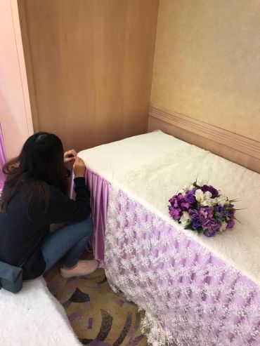 A person kneeling by a decorated table with a purple flower bouquet.